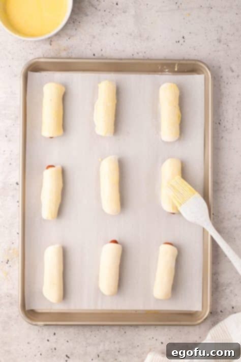 Hearty Texas Sausage Kolaches 15 A brush brushing an egg wash over Kolaches.