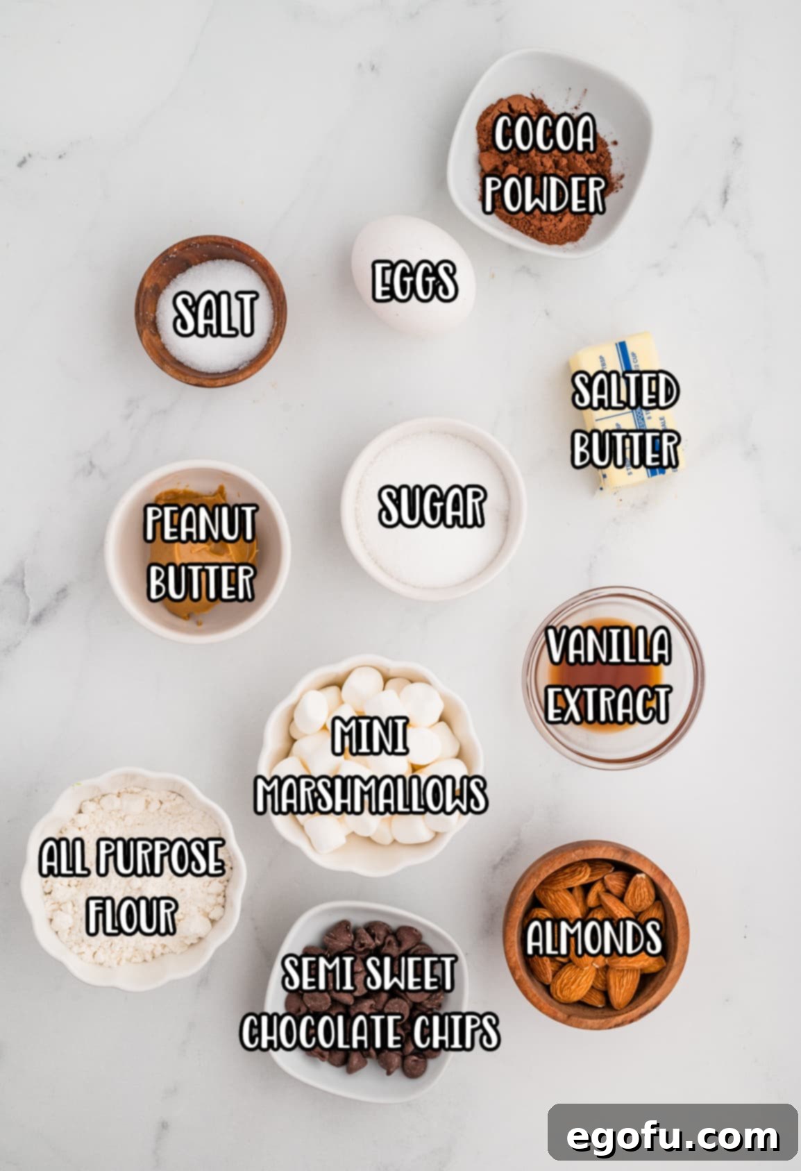 Rocky Road Bliss Bars 4 Flour, salted butter, semi-sweet chocolate chips, sugar, eggs, vanilla extract, cocoa powder, salt, peanut butter, almonds, and mini marshmallows laid out as ingredients.