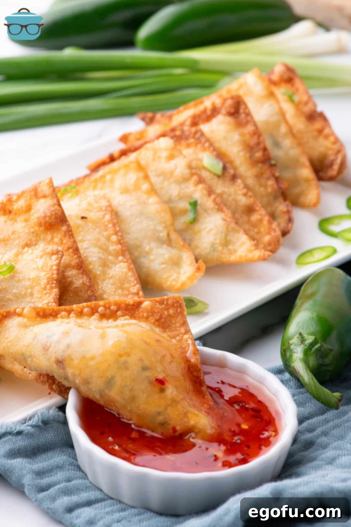 Crispy Jalapeño Wonton Poppers 2 A serving platter with some Jalapeno Popper Wontons and one in the dipping sauce.