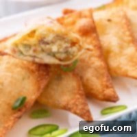 Crispy Jalapeño Wonton Poppers 12 An open Jalapeno Popper Wonton on top of the rest of the fried ones.