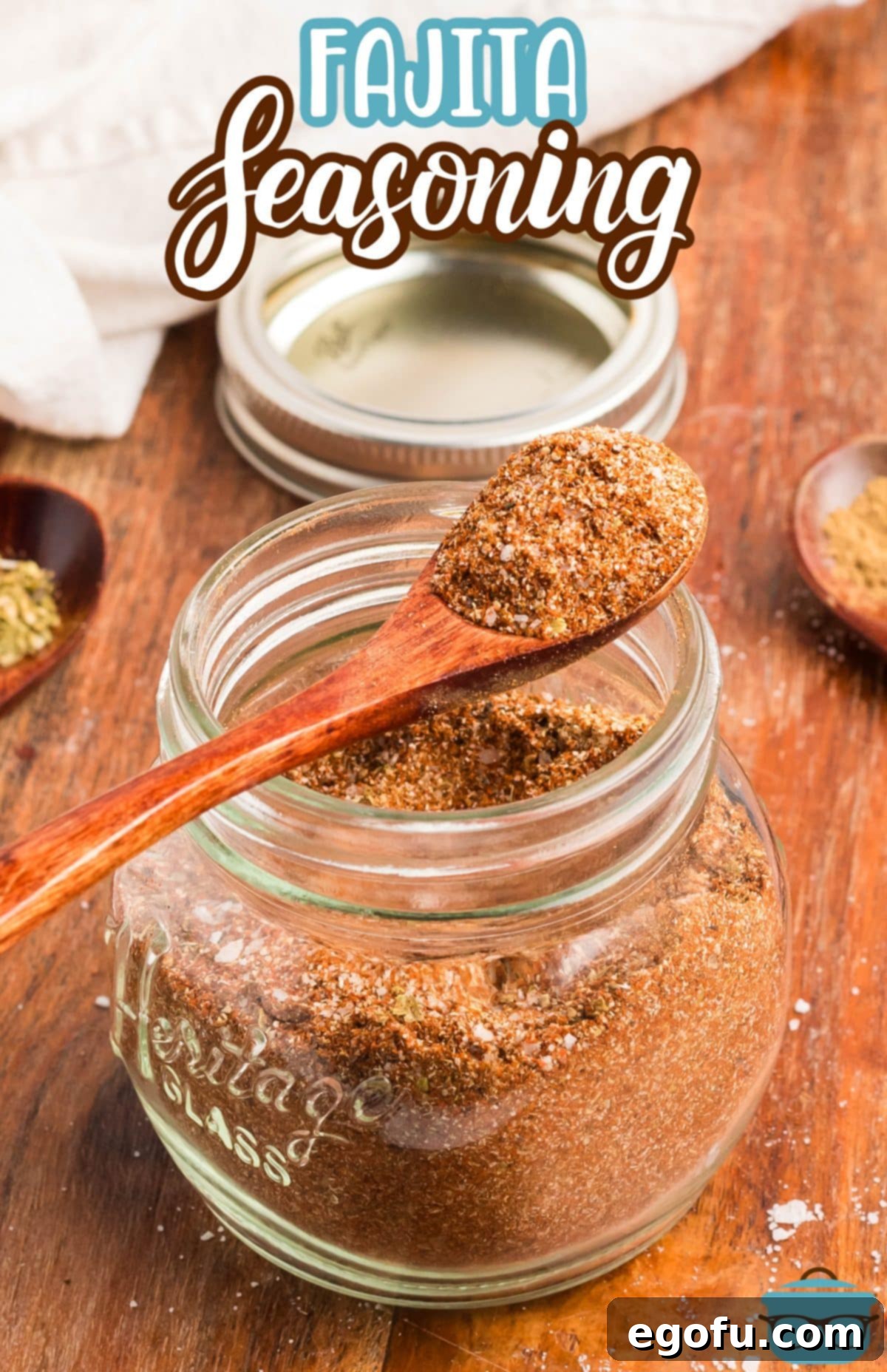 A jar with a wooden spoon holding some Homemade Fajita Seasoning.