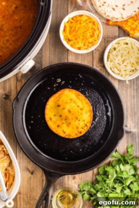 A tortilla cooking in a skillet of heated oil.