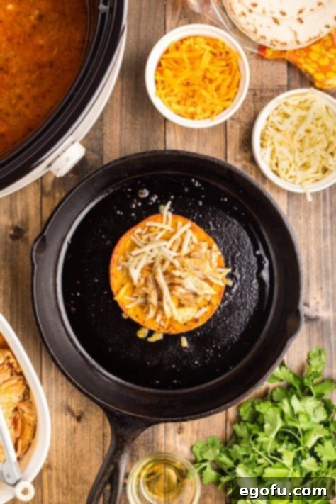 Chicken and cheese on a tortilla in a skillet.