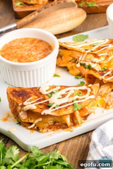 A plate of a few Buffalo Chicken Tacos with a dipping sauce and sour cream drizzle on top of the tacos.