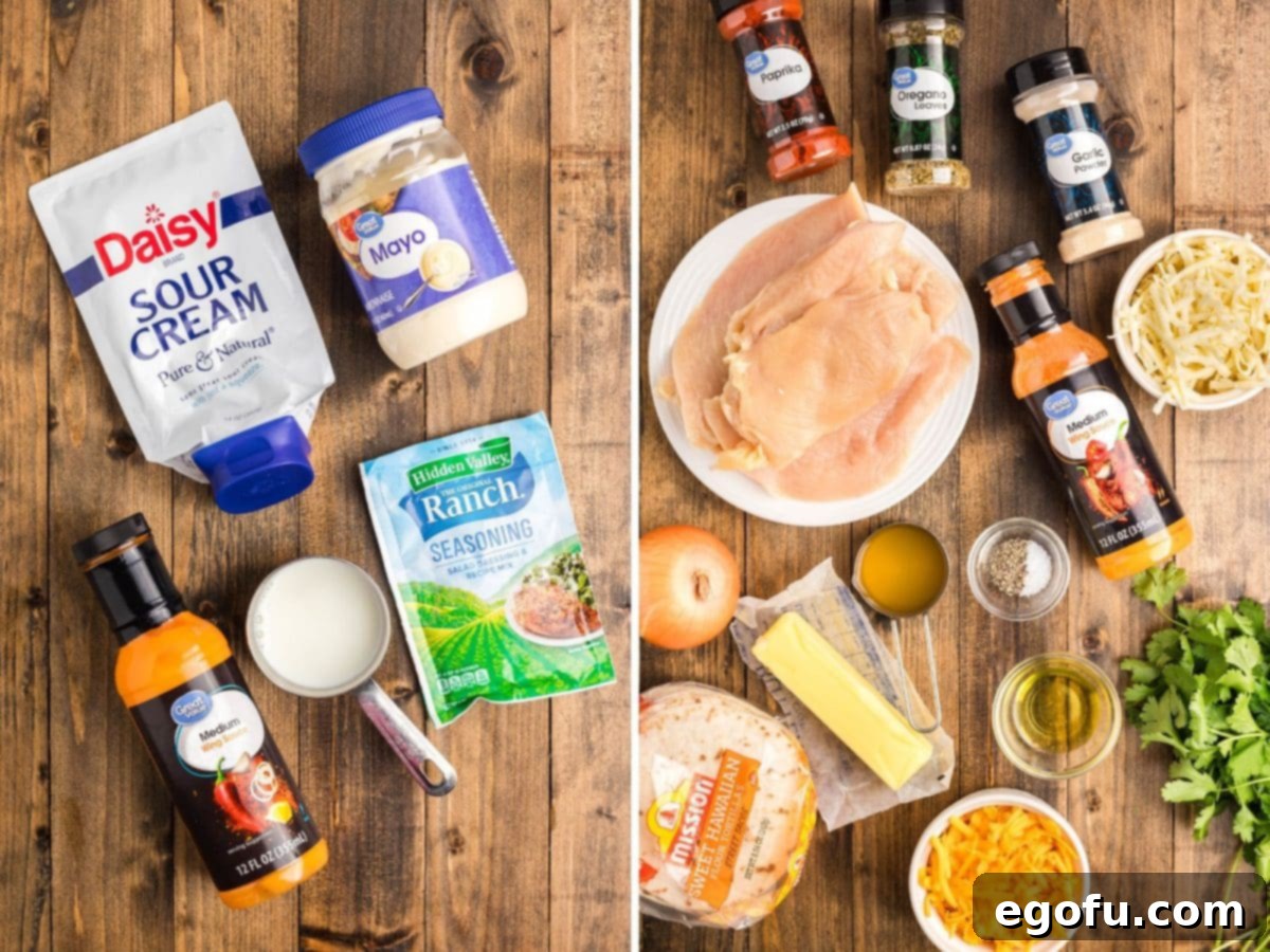 An array of ingredients for Buffalo Chicken Tacos laid out: mayonnaise, sour cream, milk, buffalo sauce, ranch seasoning, raw chicken breast, butter, yellow onion, chicken stock, dried oregano, paprika, garlic powder, kosher salt, black pepper, olive oil, street taco shells, shredded cheddar cheese, Monterey Jack cheese, and fresh cilantro.