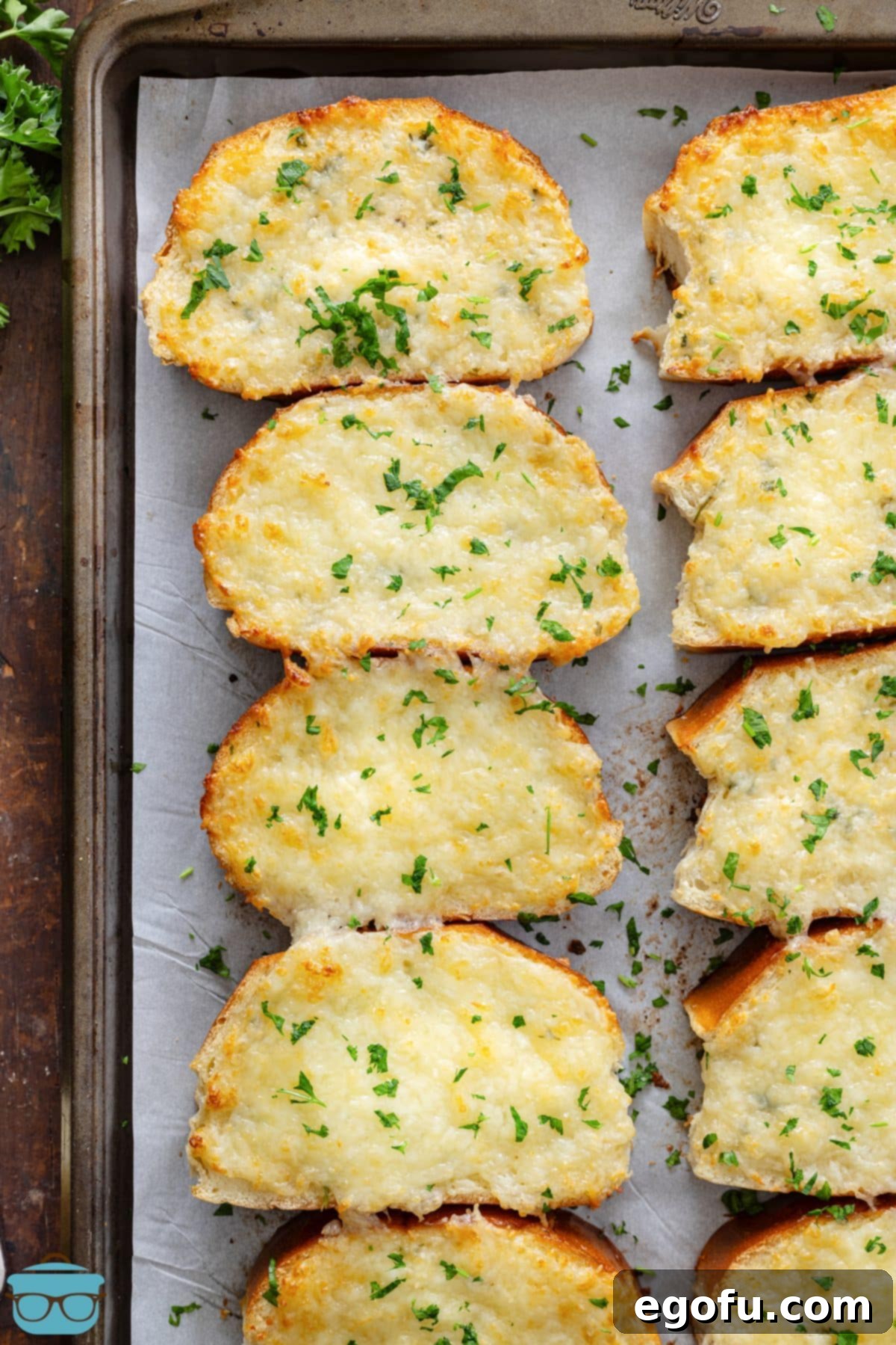 A baking sheet lined with parchment paper and some Garlic Cheese Bread.