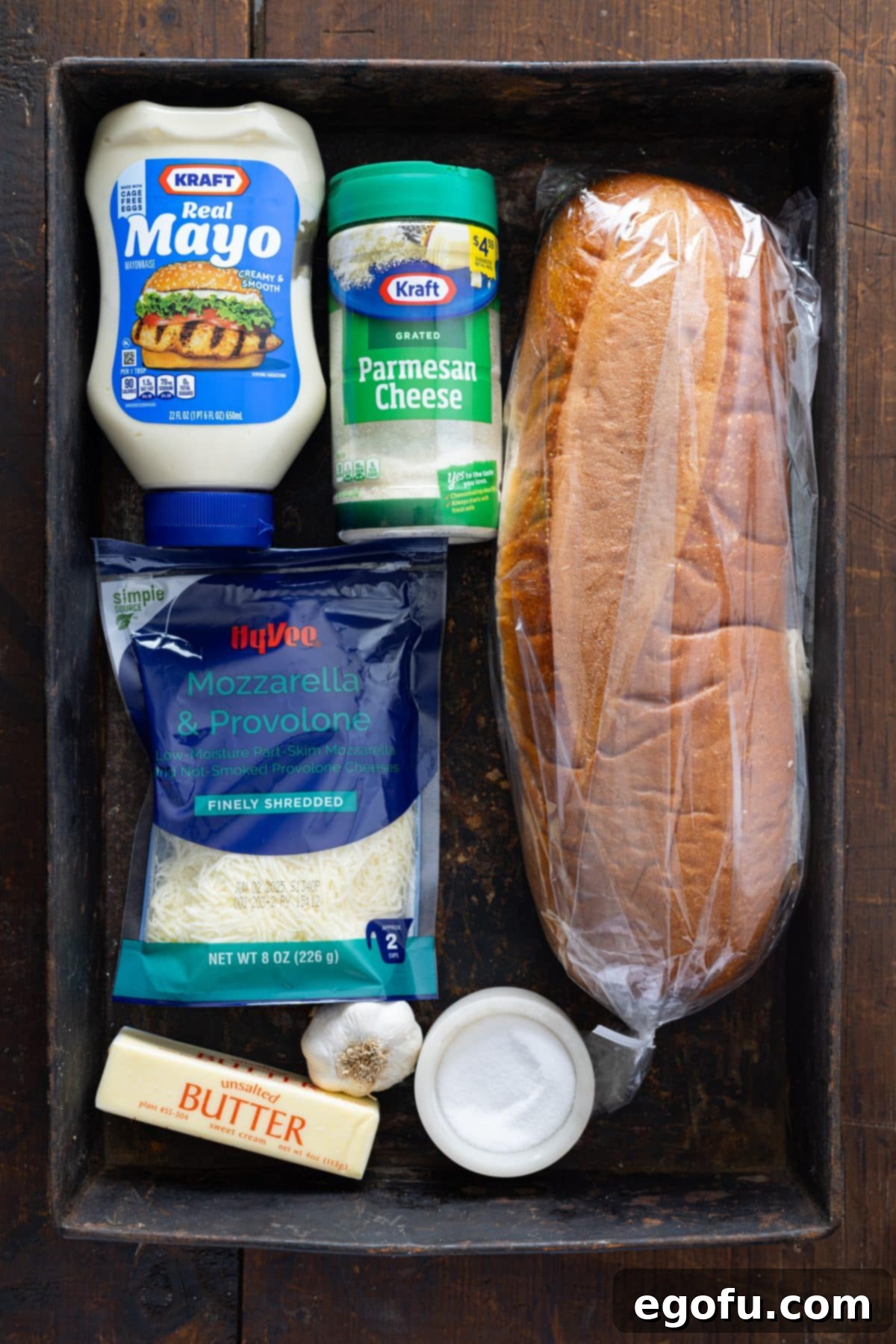 A loaf of bread, mayo, Parmesan cheese, butter, minced garlic, shredded cheese, parsley, and salt.