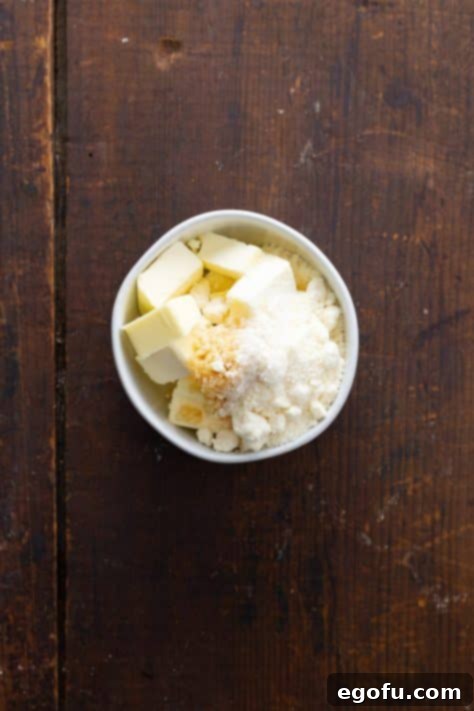 A bowl with butter, minced garlic, salt and parmesan cheese.