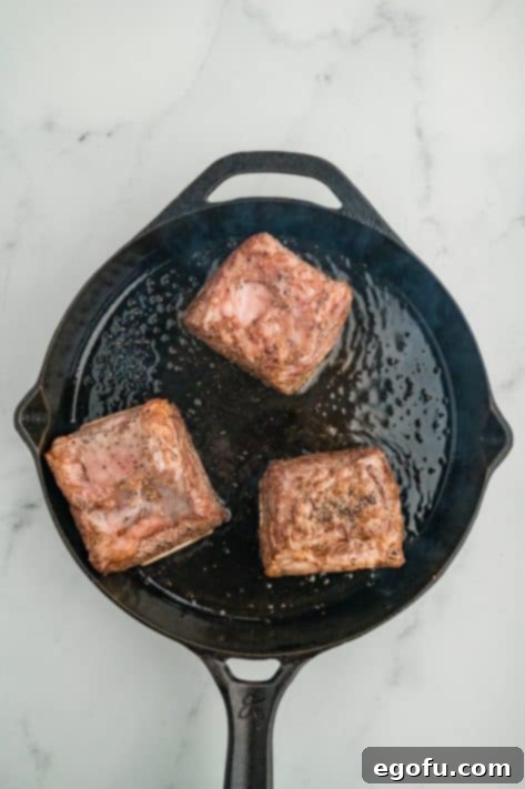 Seared short ribs in a cast iron skillet.