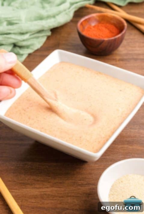 A wooden spoon stirring Yum Yum Sauce.