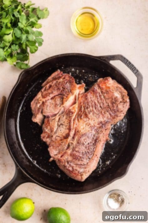Chuck roast searing in a cast iron skillet.