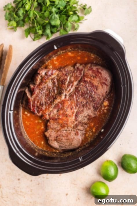 Roast being added to Crockpot with broth and seasonings.