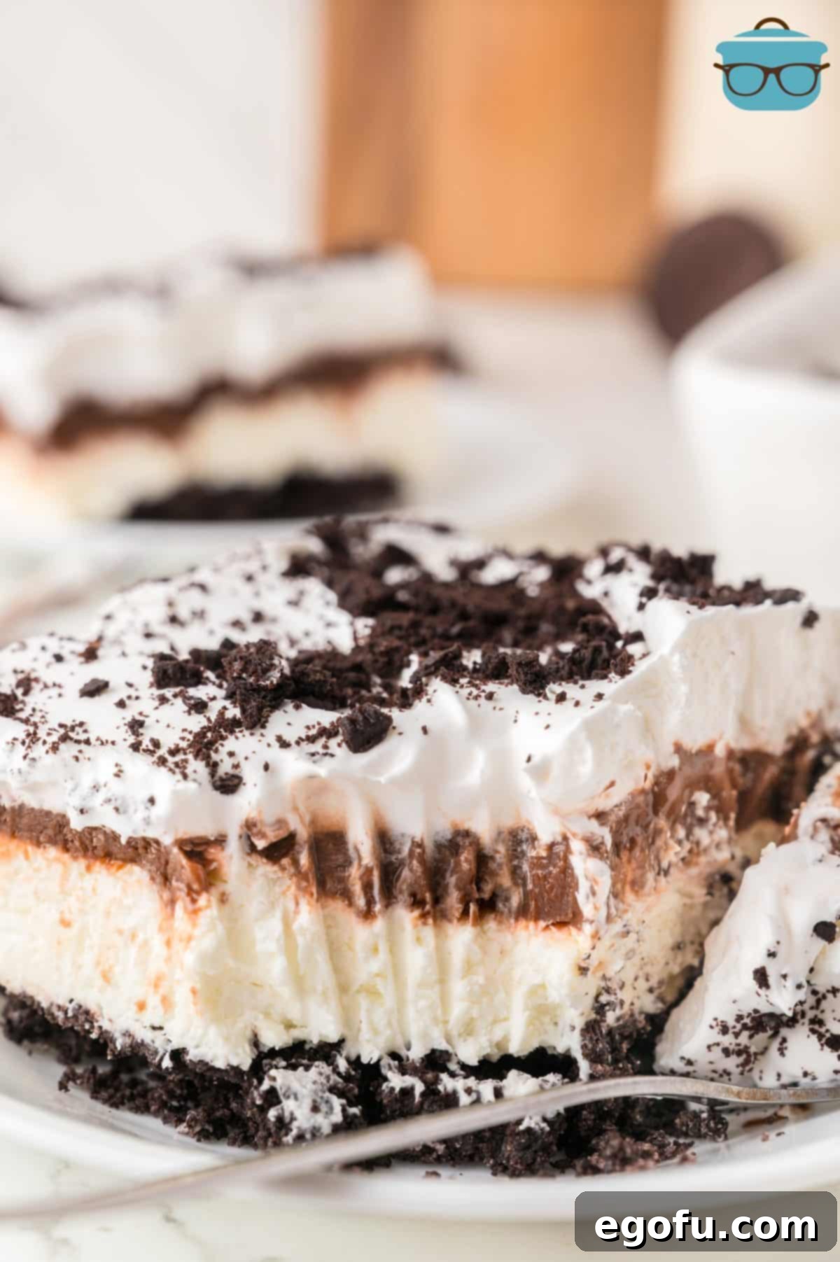 A slice of Oreo Layered Dessert with a fork holding a bite.