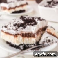 A slice of no bake Oreo Layered Dessert with a fork holding a bite.