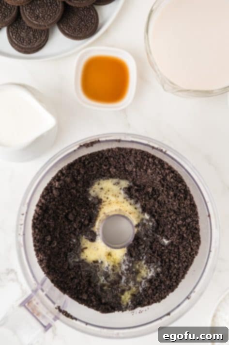 Melted butter and crushed Oreos being mixed together in a bowl.