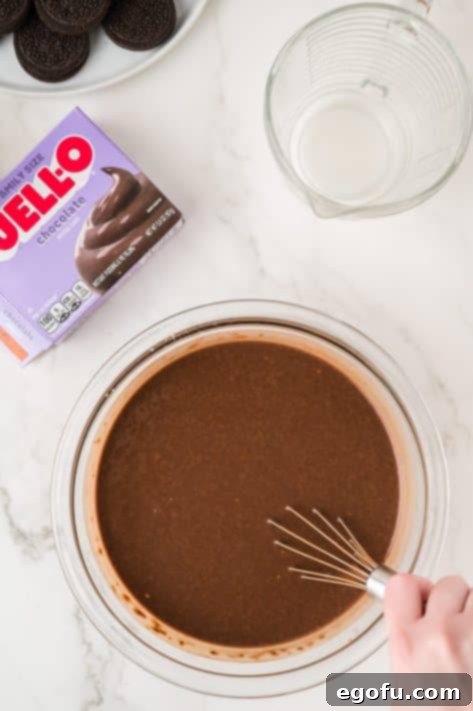 A whisk in a bowl of chocolate pudding.