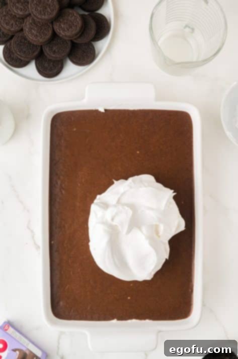 Cool Whip layer about to be spread over the chocolate pudding layer.