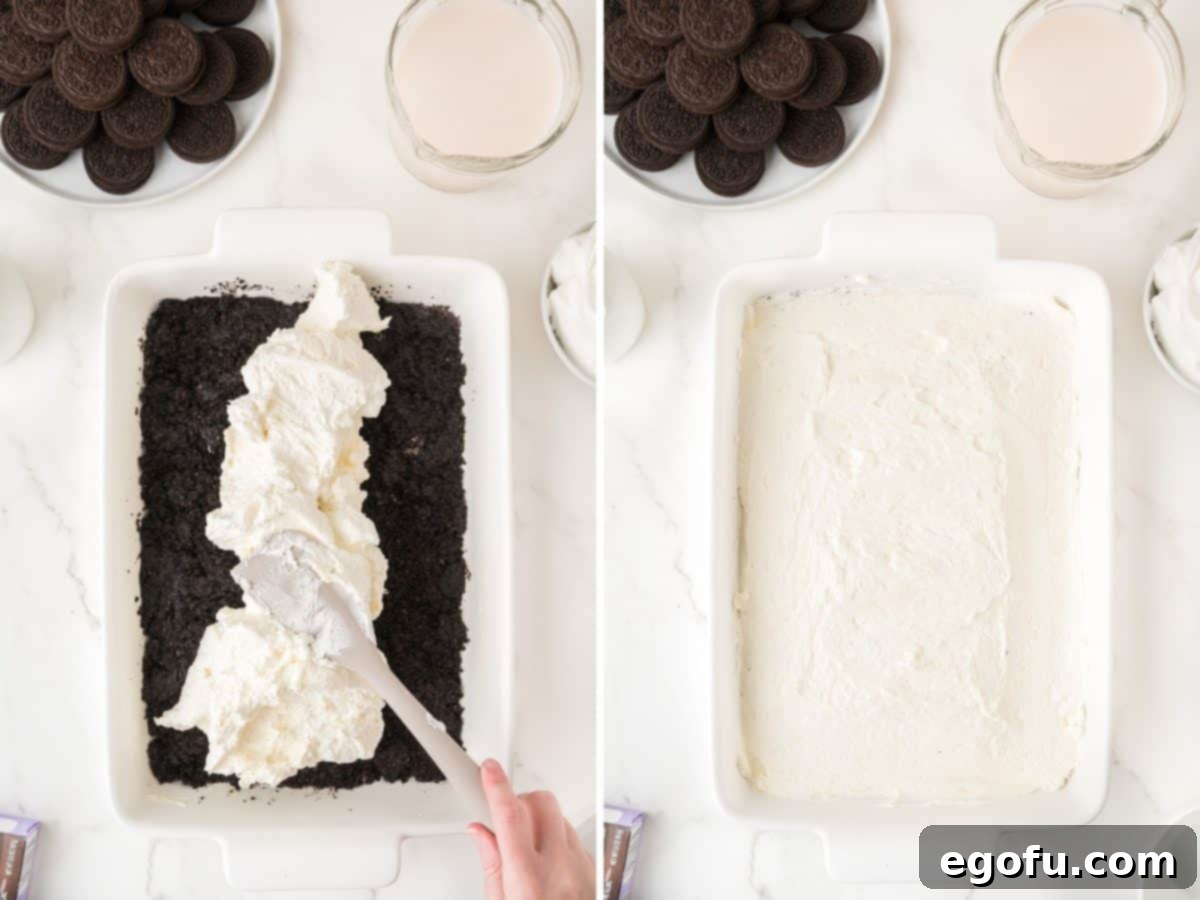 Cream cheese layer bring spread out over Oreo crust in a baking dish.