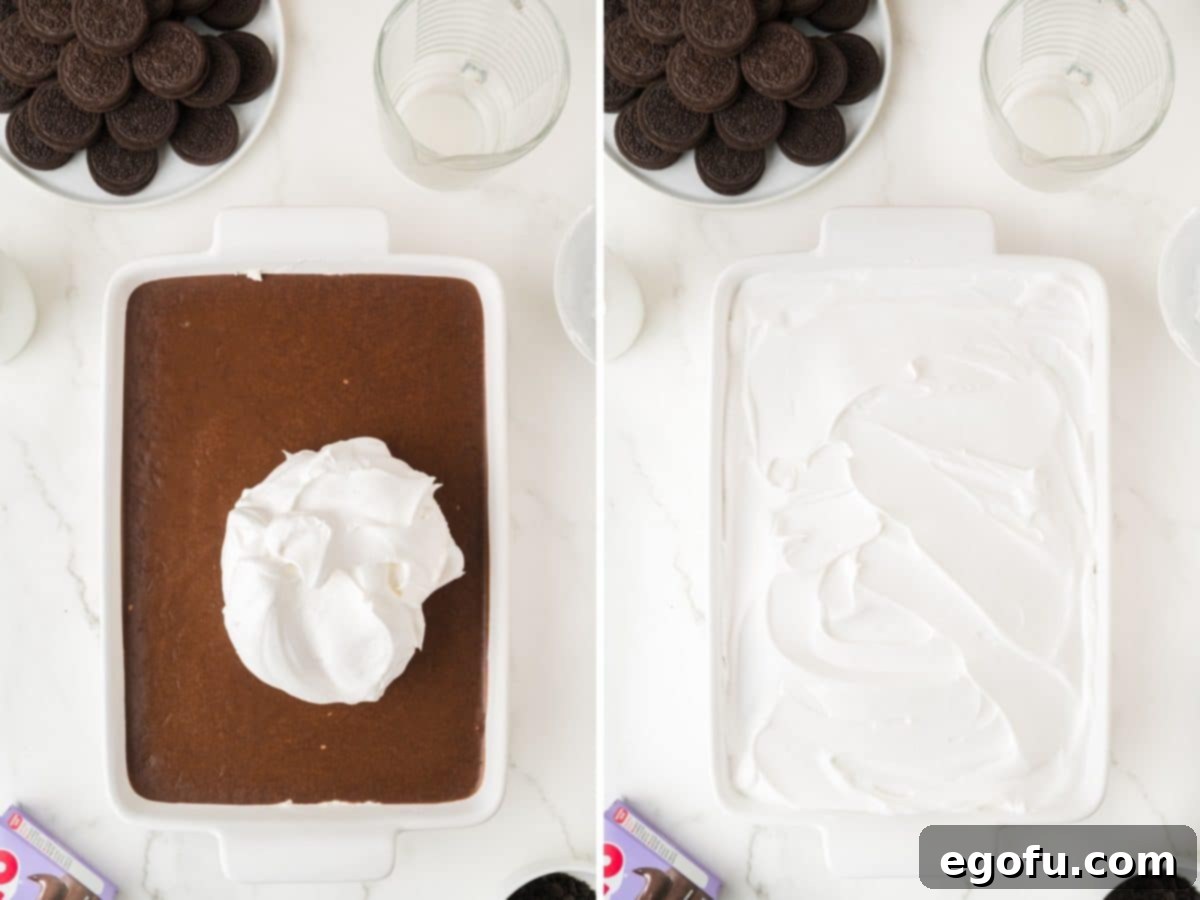 Whipped cream being spread over the chocolate pudding layer.