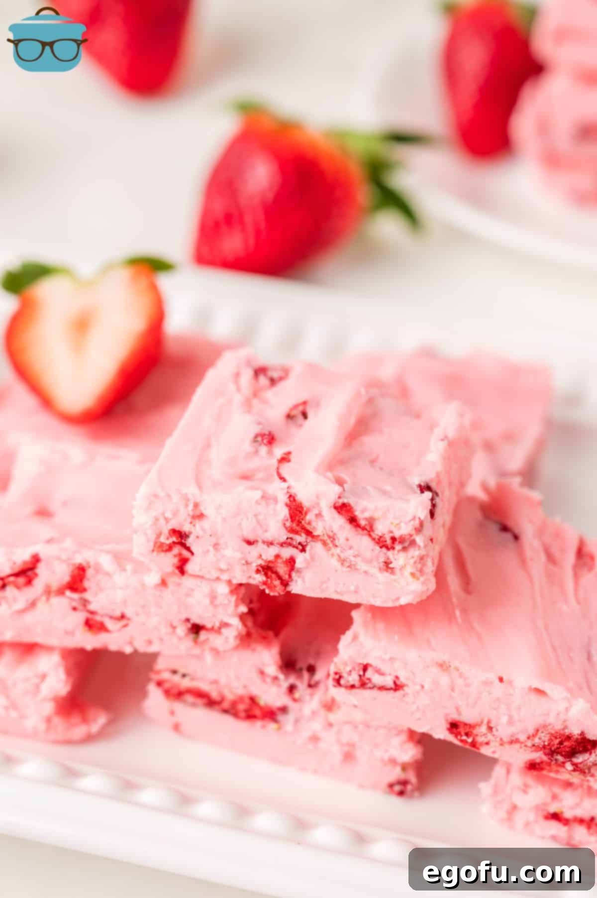 A dessert plate with a bunch of homemade Strawberry Fudge dessert, showcasing its vibrant pink color and smooth texture.