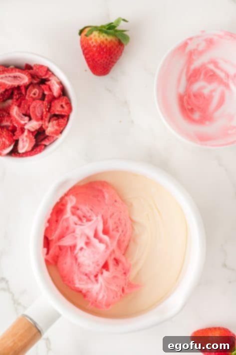 Strawberry frosting being added to melted white chocolate chips.