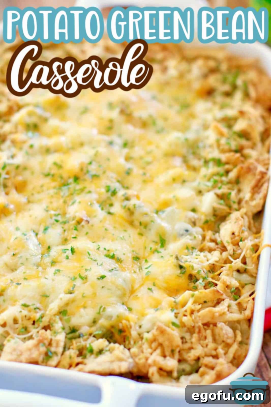 Homestyle Potato Green Bean Bake 3 A close-up view of a fully baked Tater Green Bean Casserole in a pristine white baking dish, showcasing its golden-brown topping and creamy interior, ready to be enjoyed.