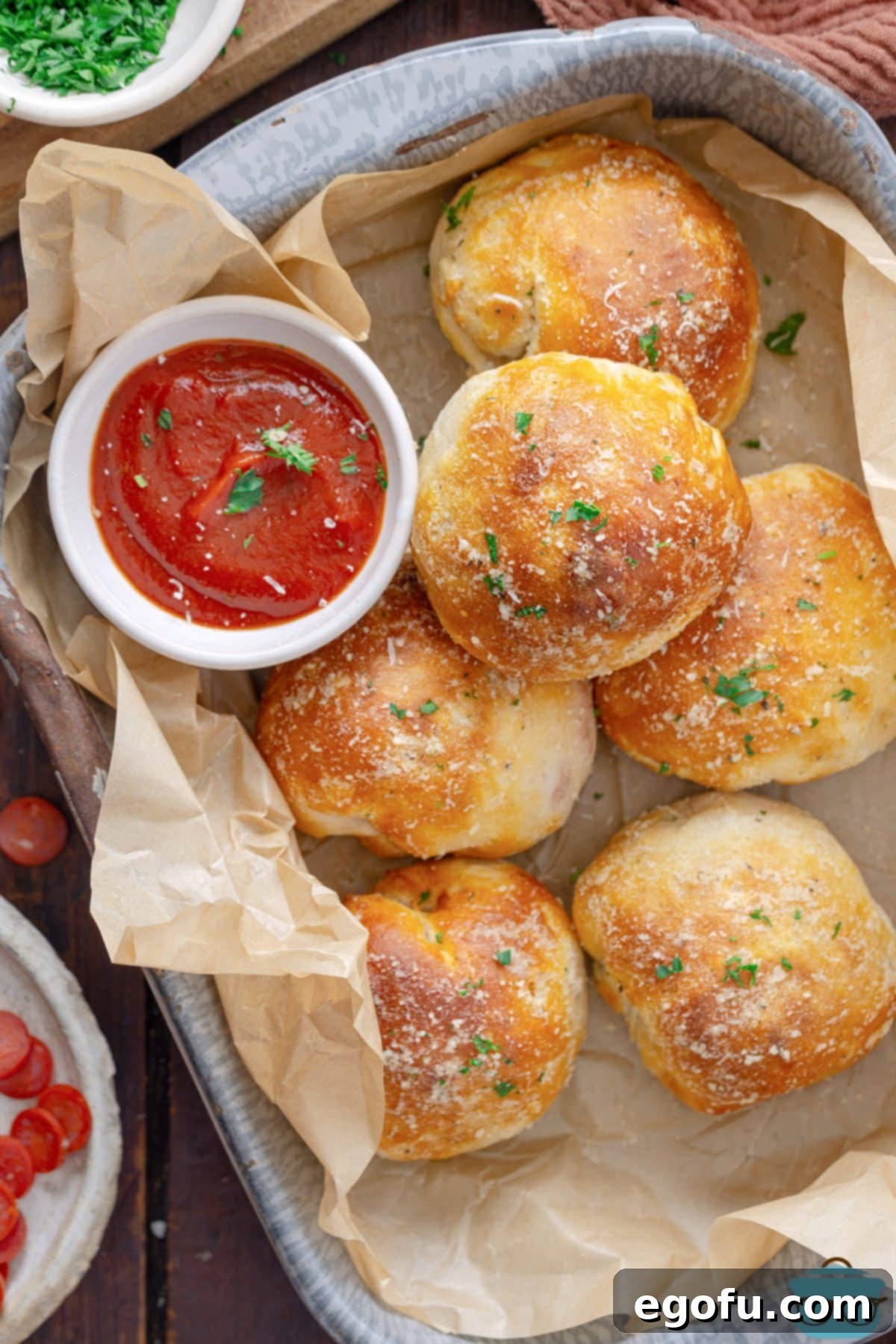 A lined baking dish filled with a generous batch of cooked and glazed Air Fryer Pizza Bombs.