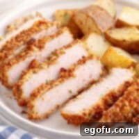 A Crispy Baked Pork Chop sliced up with potatoes on a plate.