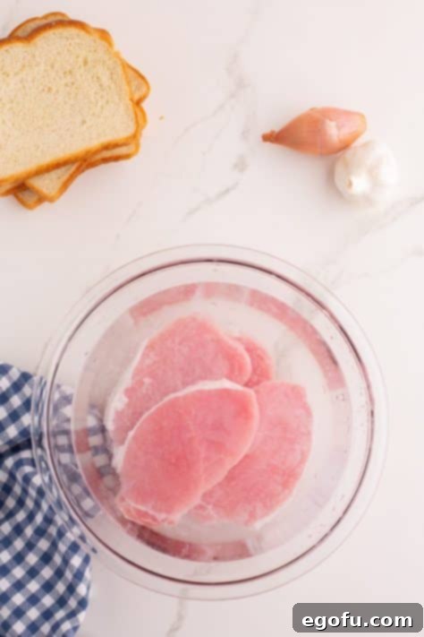 A bowl of pork chops sitting in a brine.