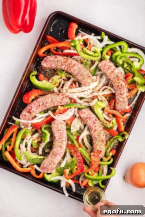 One Pan Sausage and Pepper Bake 8 A sheet pan with uncooked sausage and veggies.
