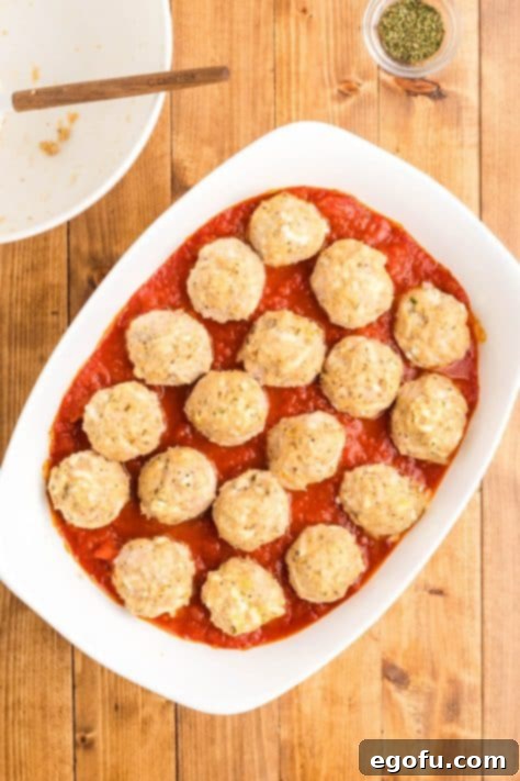 Chicken Parm Meatball Bake 14 Baked meatballs in a pool of marinara sauce after the initial baking phase.