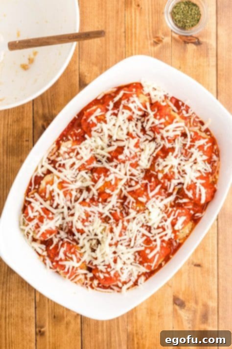 Chicken Parm Meatball Bake 15 Chicken Parmesan Meatballs generously covered with marinara sauce and shredded cheese, ready for final baking.