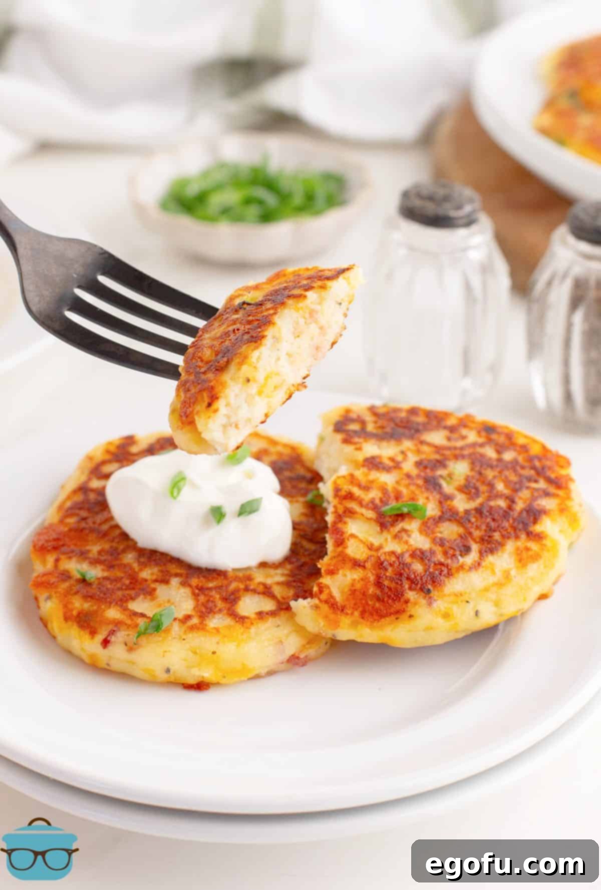 Crispy Potato Fritters 7 A fork holding a bite of Potato Cakes above a few on a plate.