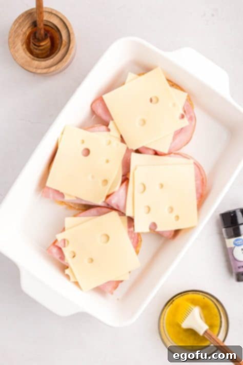 A baking dish with croissant roll bottoms, ham and cheese slices.