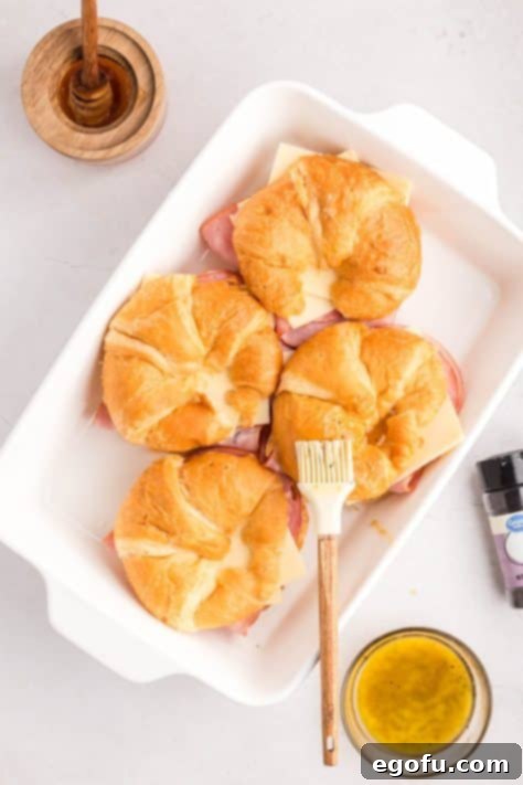 A pastry brush brushing melted butter mixture on top of rolls.