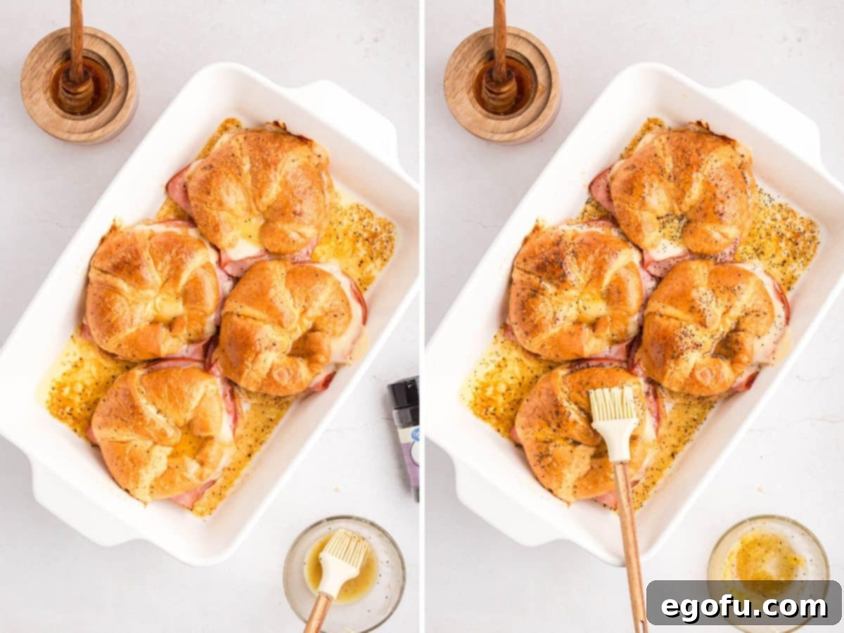 Baked Ham and Cheese Croissants with poppy seeds and butter sauce being brushed on tops.