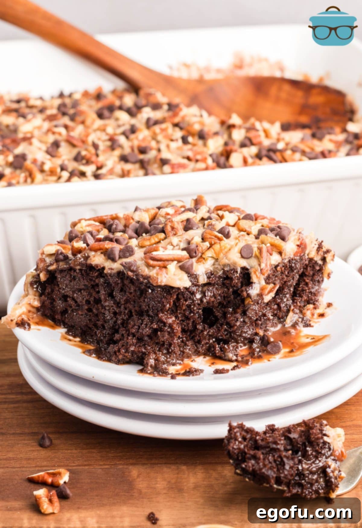 A beautifully presented slice of German Chocolate Poke Cake with visible layers of moist cake, chocolate filling, and coconut pecan frosting.