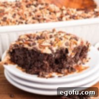 A stack of dessert plates with a large slice of German Chocolate Poke Cake.