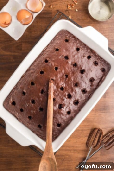 A wooden spoon poking holes in a German Chocolate Poke Cake.