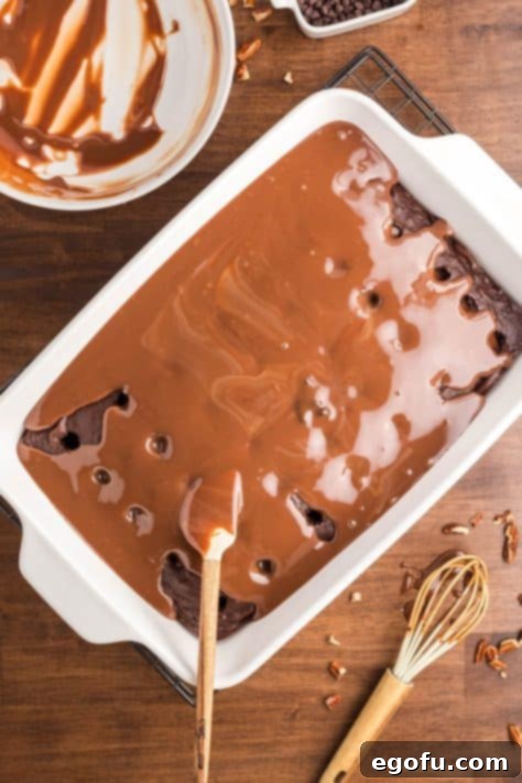 Chocolate sauce soaking into a German chocolate cake with holes.