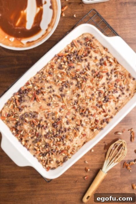 Pecans and mini chocolate chips on top of a frosted German Chocolate Poke Cake.