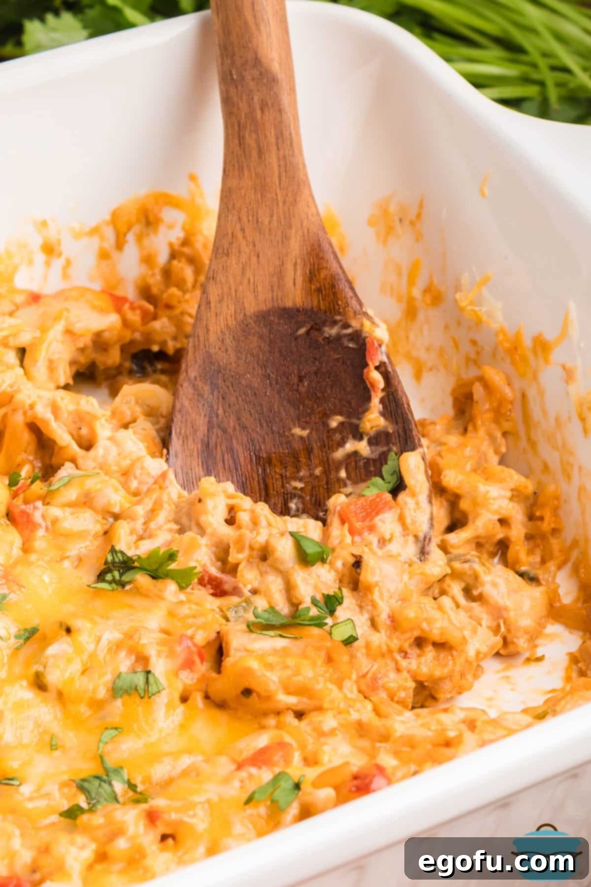 A wooden spoon getting a scoop of Chicken Fajita Casserole.