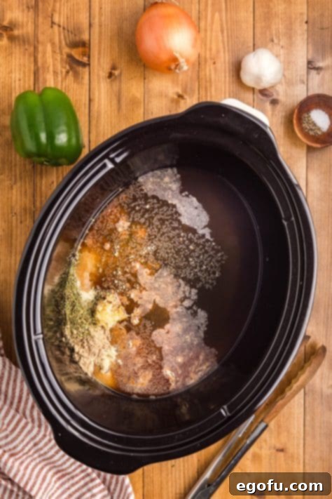 A Crock Pot with beef broth, au jus, minced garlic, Italian seasoning, garlic powder, and onion powder.