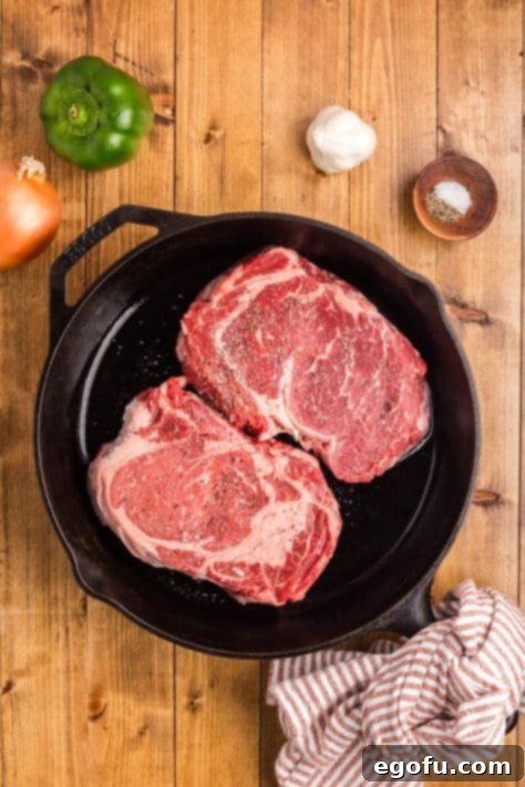 Steaks in a skillet with salt and pepper.