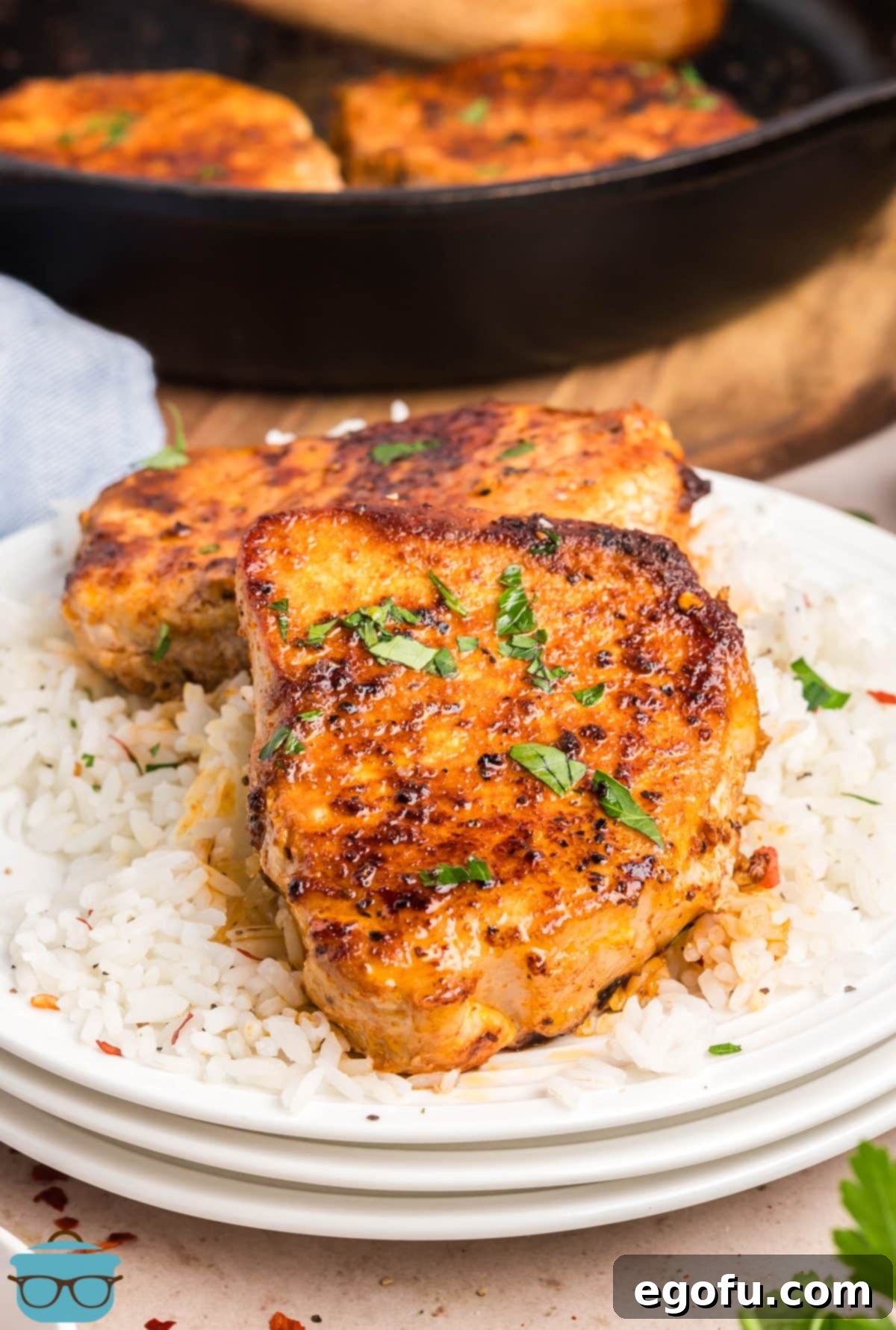 Two Quick Skillet Pork Chops on a small stack of plates, garnished with fresh parsley.
