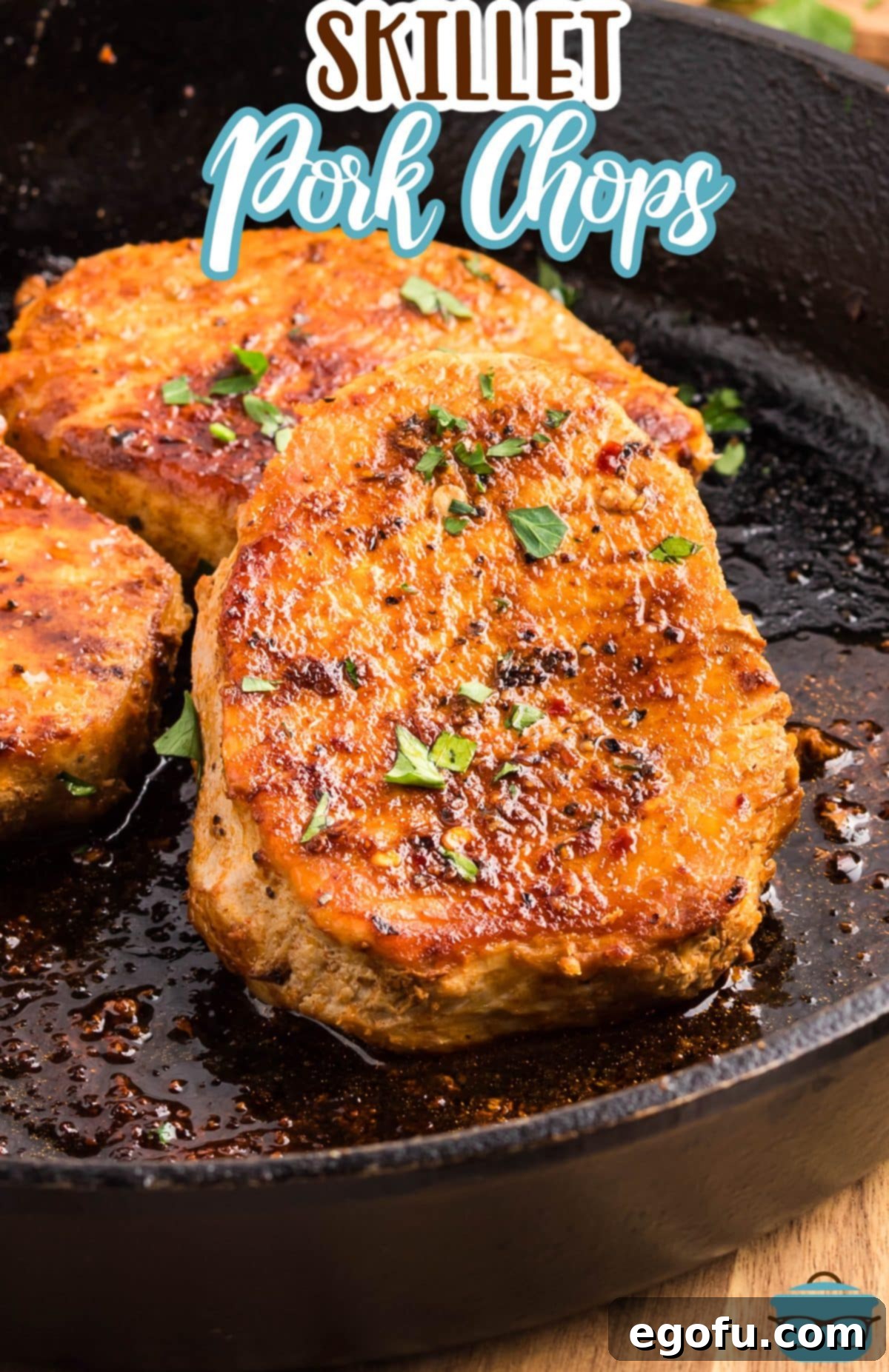 A cast iron skillet with golden-brown skillet seared Pork Chops, ready to serve.