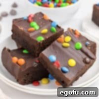 A small plate of homemade Cosmic Brownies, showing their rich texture and colorful M&M topping.