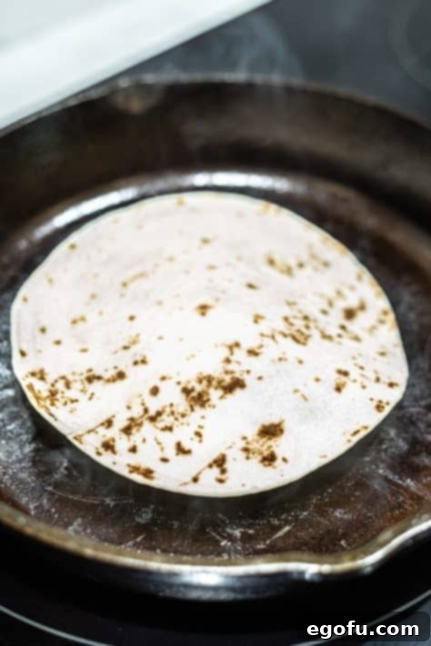 MacSmash Taco 13 Beef under a tortilla searing in a hot skillet.