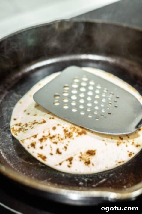 MacSmash Taco 14 Spatula pushing beef and a tortilla on a hot pan for smashing.