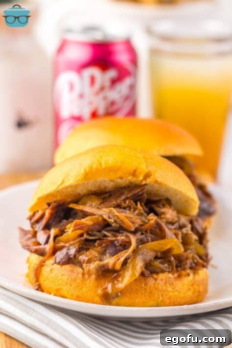 Tender Dr Pepper Slow Cooker Pulled Beef 12 Crock Pot Shredded Beef on a bun on a plate.